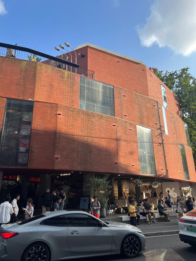 Sunlit red brick building above a busy sidewalk