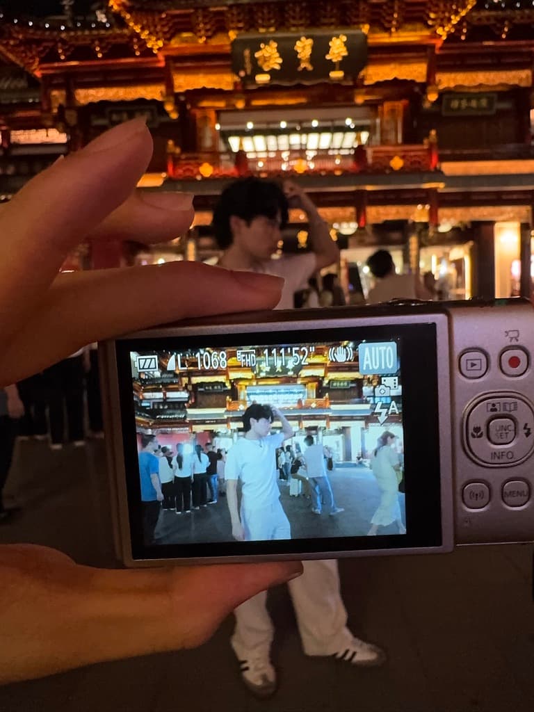A compact camera framing a portrait in front of an illuminated building