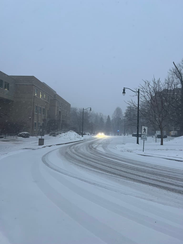 Snow-covered curved street with approaching headlights